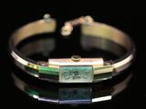 un gros plan d'un bracelet orné d'un motif vert et doré