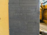 une plaque apposée sur le mur latéral d'un immeuble jaune