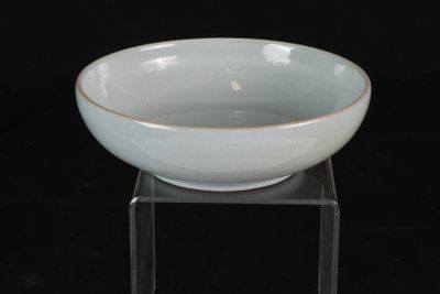 un bol blanc posé sur un socle transparent, sur un fond noir