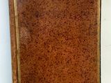 un vieux livre marron, muni d'une étiquette, posé sur une table