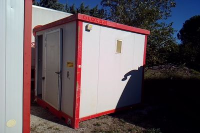 des toilettes portables rouges et blanches posées dans l'herbe