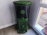 une poubelle noire et verte posée devant une fenêtre