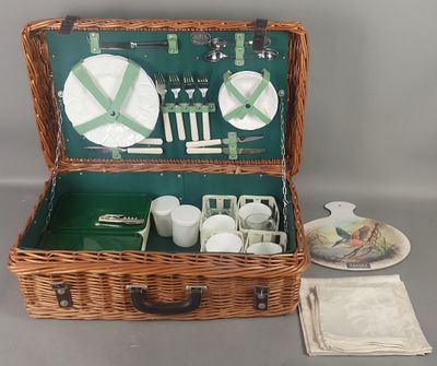 un panier de pique-nique en osier contenant des assiettes, des tasses et des soucoupes