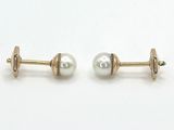 deux paires de boucles d'oreilles à clous en or et perles, posées sur un fond blanc