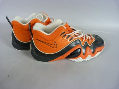 an orange and black shoe with white laces on a white surface