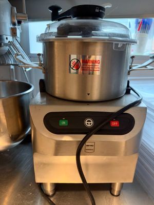 une grande casserole posée sur un plan de travail, à côté d'un robot ménager