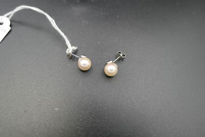 une paire de boucles d'oreilles en perles posées sur une surface noire, avec une étiquette de prix