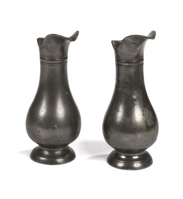 deux vases en argent posés l'un à côté de l'autre sur une surface blanche