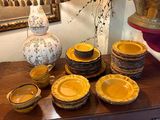 de nombreuses assiettes et bols posés sur une table, avec un vase en arrière-plan