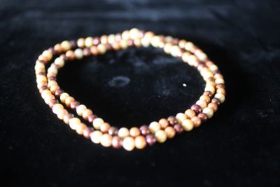 un gros plan d'un bracelet en perles posé sur une surface noire