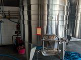 stainless steel tanks are lined up in a room with a hose
