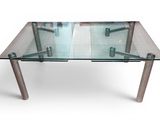 une table en verre avec des pieds en métal et un plateau en verre