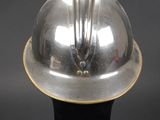 an image of a silver fireman ' s helmet on a black stand