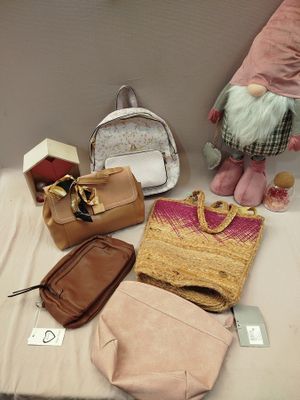 many bags and purses on a table next to a stuffed gnome