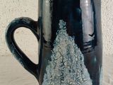 a black and blue coffee mug with a mountain design on it