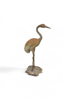 statue d'une grue debout sur un rocher, posée sur un fond blanc