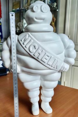 une statue blanche représentant un homme corpulent tenant une règle