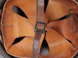 an old helmet with a leather strap on a black surface
