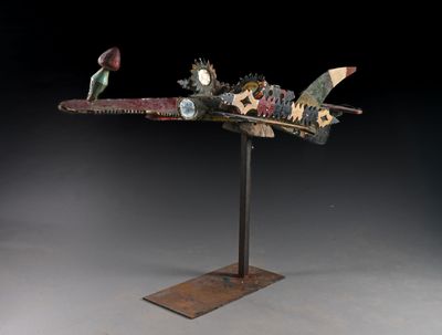 sculpture représentant un avion, composée d'engrenages et de roues dentées, posée sur un socle métallique