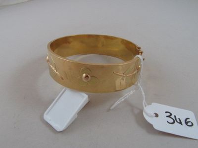 un bracelet en or posé sur une table blanche, avec une étiquette de prix