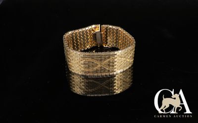 une image montrant un gros plan d'un bracelet en or posé sur une surface noire