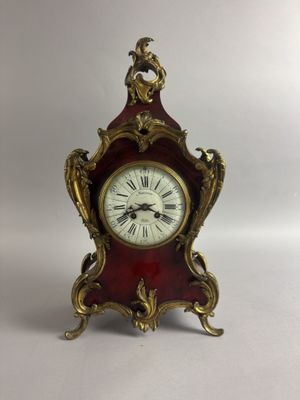 une petite horloge rouge surmontée d'un oiseau