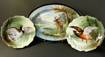 three plates with birds painted on them sitting on a table