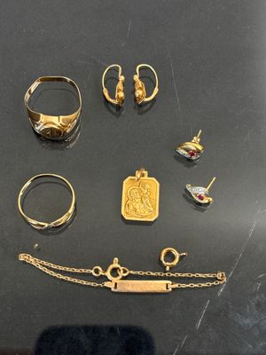 plusieurs bagues en or, des bracelets et d'autres bijoux posés sur une table