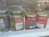many jars of pickles on the shelf in the refrigerator