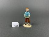 miniature figurine of a man holding a book next to a white block