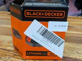 une boîte orange et noire contenant des piles Black & Decker, posée sur une table en bois