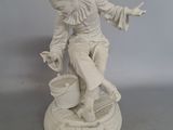 une statue blanche représentant un homme avec un seau posé sur une table