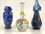 four glass vases are lined up on a white surface