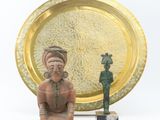 a statue of a man sitting next to a gold plate