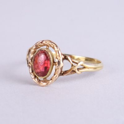 Gros plan sur une bague en or ornée d'une pierre rouge