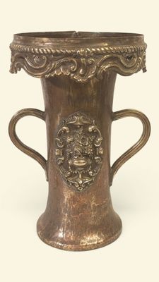 un vase en bronze muni d'une anse, sur fond blanc