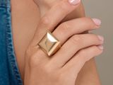 the woman is wearing a gold ring with a square design