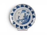une assiette bleue et blanche sur laquelle est représenté un homme sur un pont