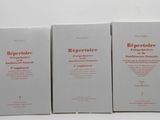 trois livres posés sur une table blanche, avec des inscriptions rouges dessus