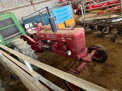 un tracteur qui se trouve dans une grange avec d'autres tracteurs