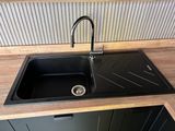 a black kitchen sink with a black faucet in it