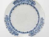une assiette bleue et blanche posée sur un support sur une surface blanche