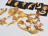 a lot of gold brooches and brooches on a table