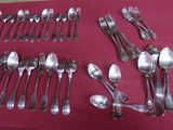 un grand nombre de cuillères et de fourchettes disposées sur une table
