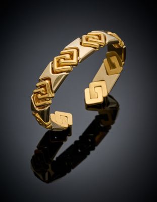 gros plan d'un bracelet en or sur une surface noire