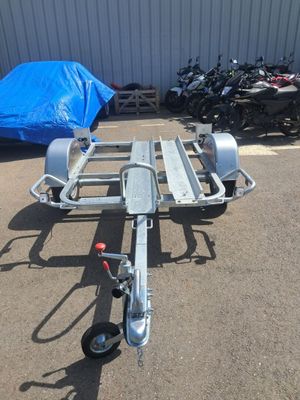 une remorque à laquelle est attelée une moto, dans un parking