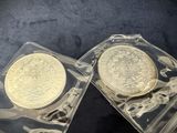 two gold coins in a clear case on a black surface