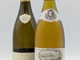 deux bouteilles de vin posées l'une à côté de l'autre sur une surface blanche