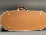 a close up of a brown leather bag on a gray surface