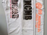 three pairs of white sweatpants hanging on a wall with a clock in the background